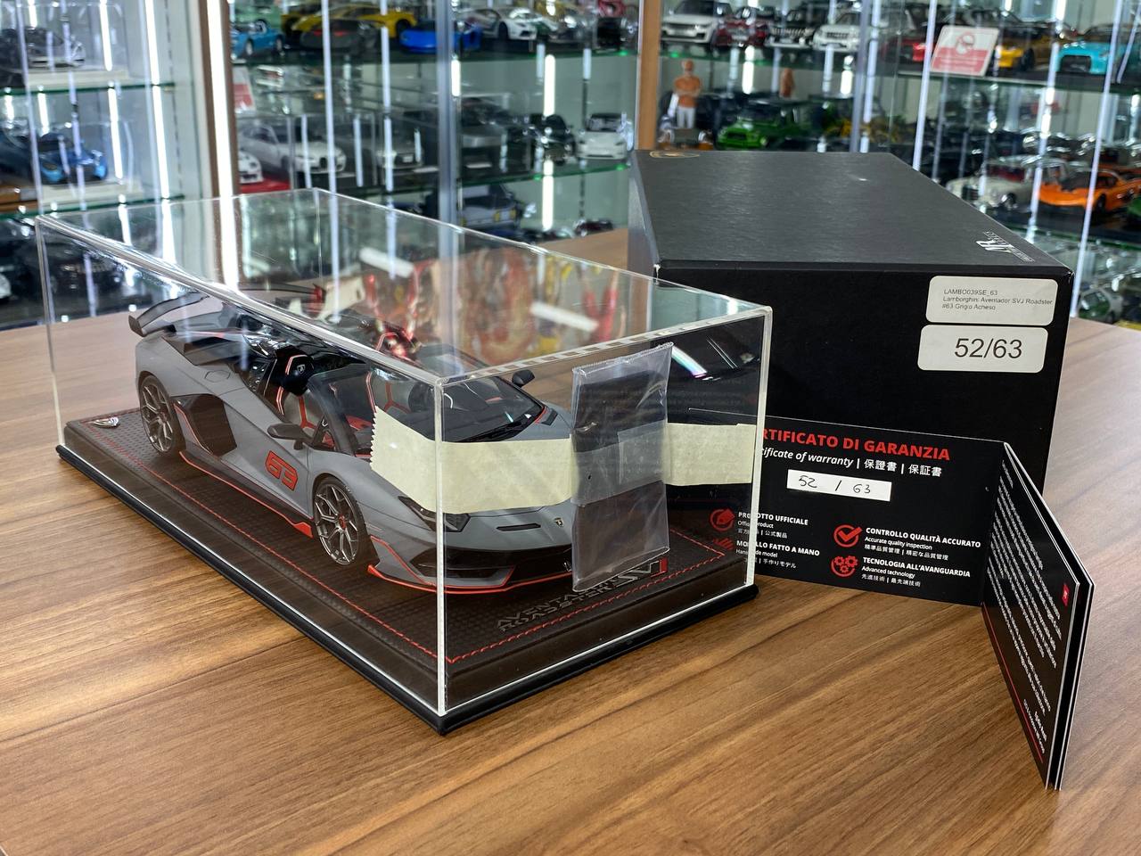 Model car in a clear display case with a black box labeled '52/63' on a wooden surface.